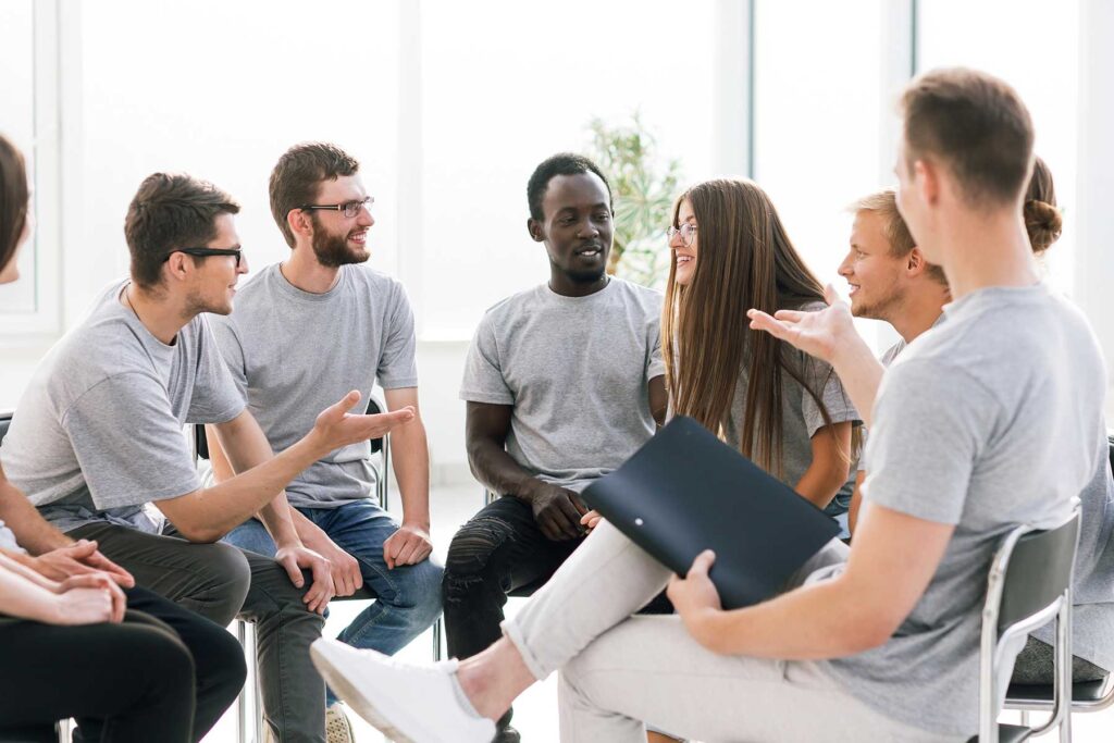 people sitting in a circle discuss the benefits of group therapy