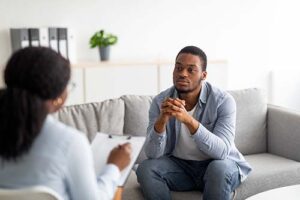 man in a behavioral addiction treatment program talks with a therapist