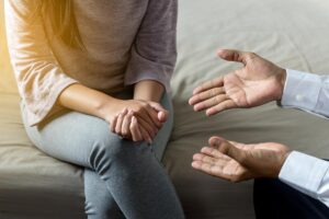 Hands of a person explaining to a client why a massage therapy program is beneficial for addiction treatment